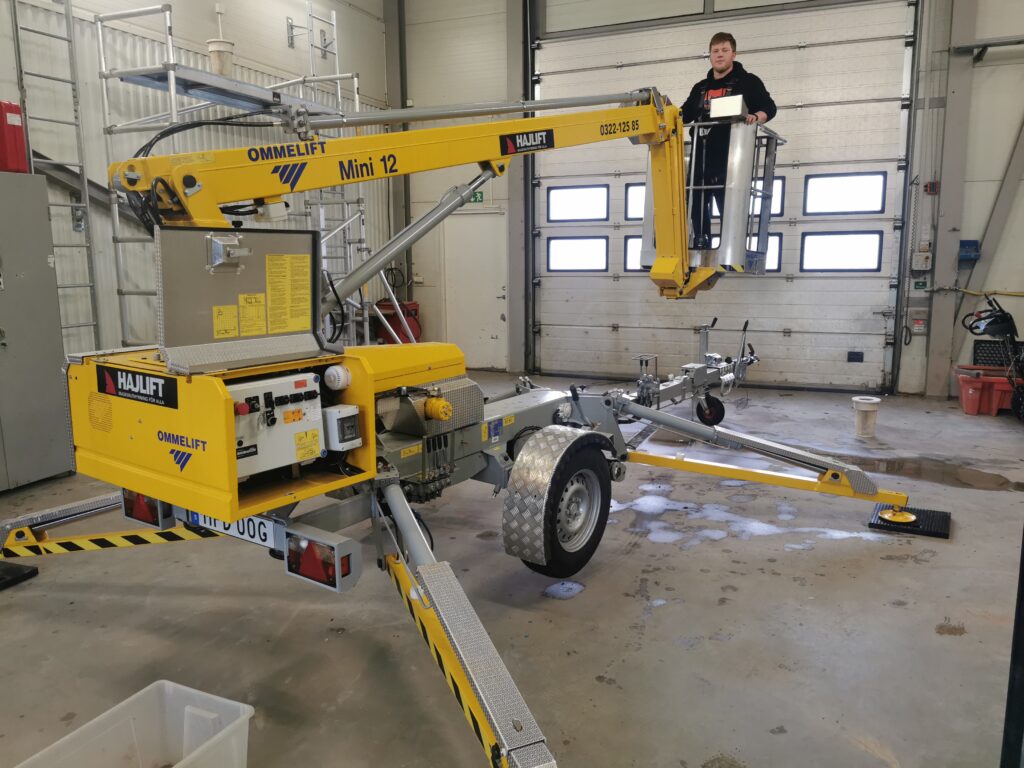 man står på en gul lift inomhus